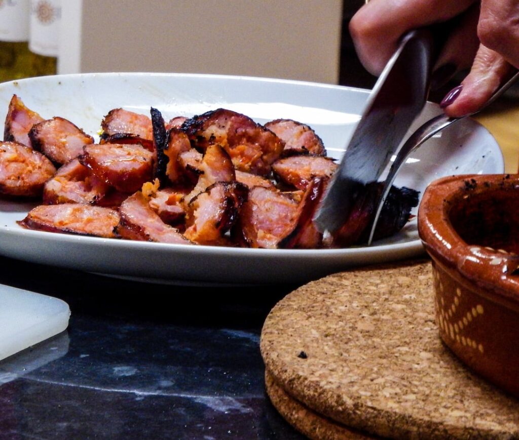 Flame-grilled Portuguese chouriço sliced into bite-sized pieces ready to serve.