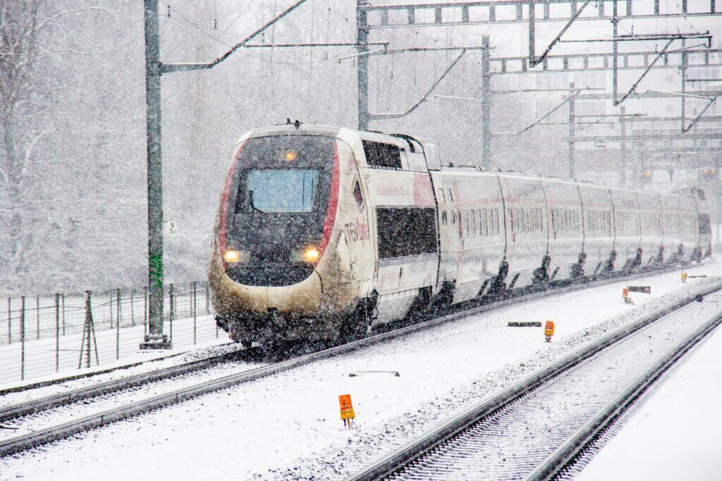 Snow-dust-topped railroad tracks leading to a blue-and-white train in Dietikon, Switzerland
