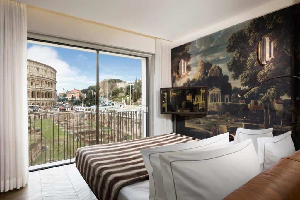 Luxurious room at Hotel Palazzo Manfredi in Rome with floor-to-ceiling windows overlooking the Colosseum and Roman Forum ruins.
