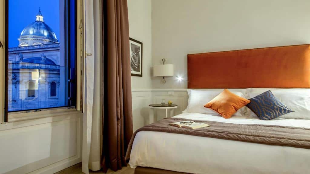 Bright modern bedroom at Princeps Boutique Hotel in Rome with burnt orange headboard and a view of the dome of Santa Maria Maggiore.