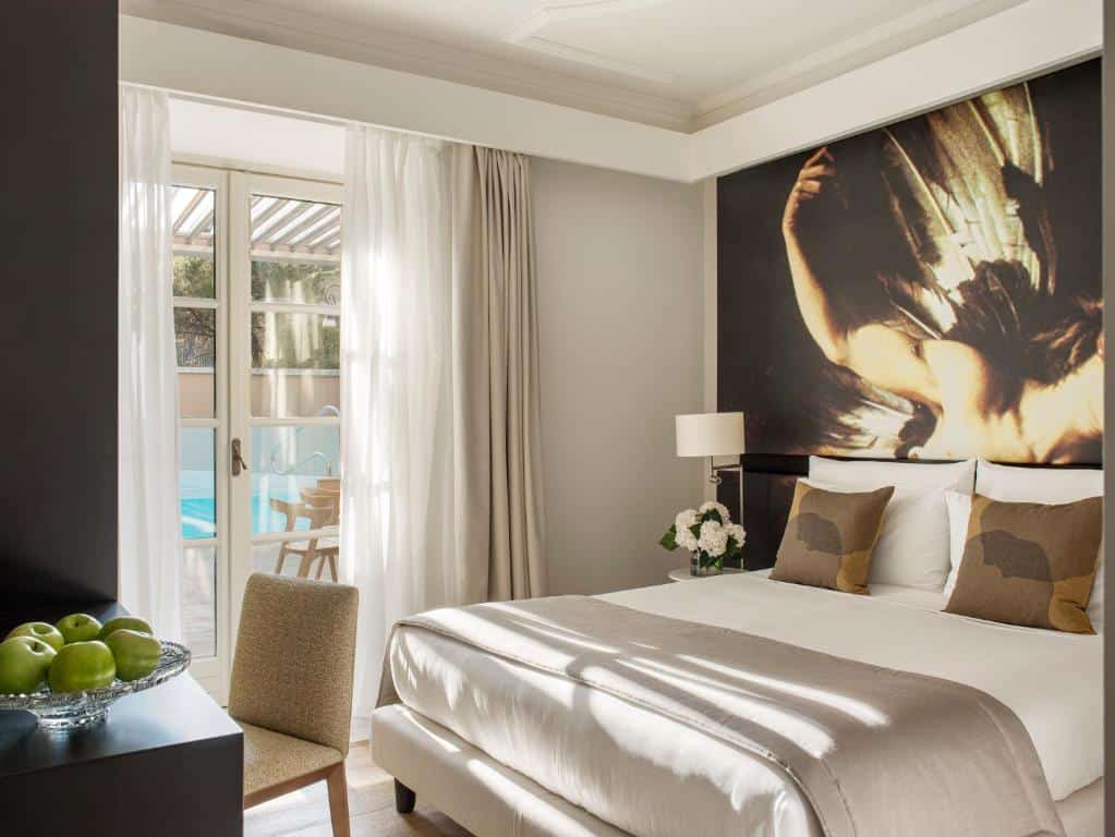 Elegant neutral-toned room at Villa Agrippina Gran Meliá in Trastevere, Rome, with modern artwork and balcony overlooking the pool.