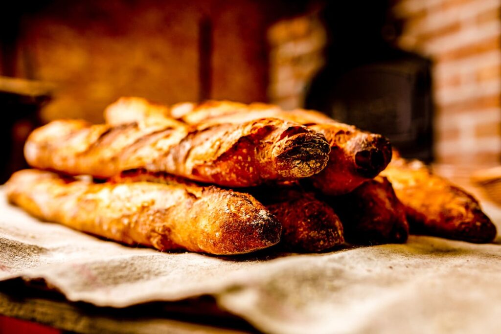 Freshly baked French baguettes stacked in a Paris bakery with a golden crust.