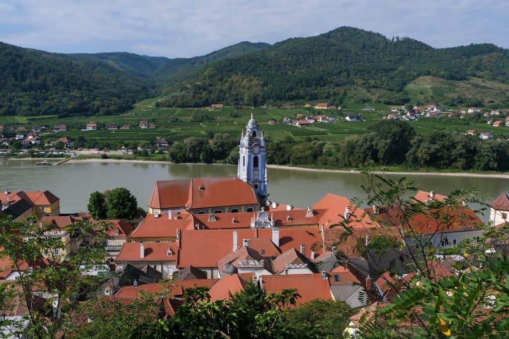 Melk Abbey overlooking the Danube River in Austria’s Wachau Valley with vineyards and rolling hills in the background.