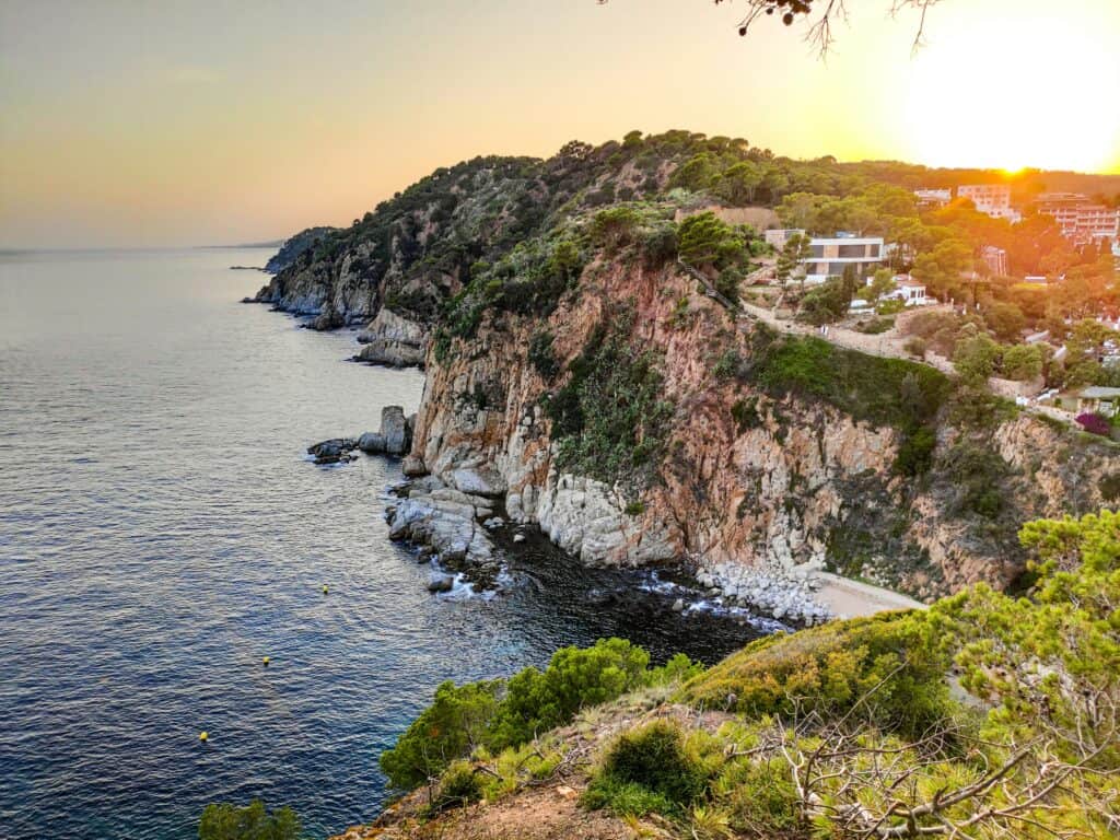 Sunset over Tossa de Mar on the Costa Brava, Spain, with golden light on the medieval castle and town walls overlooking the sea.
