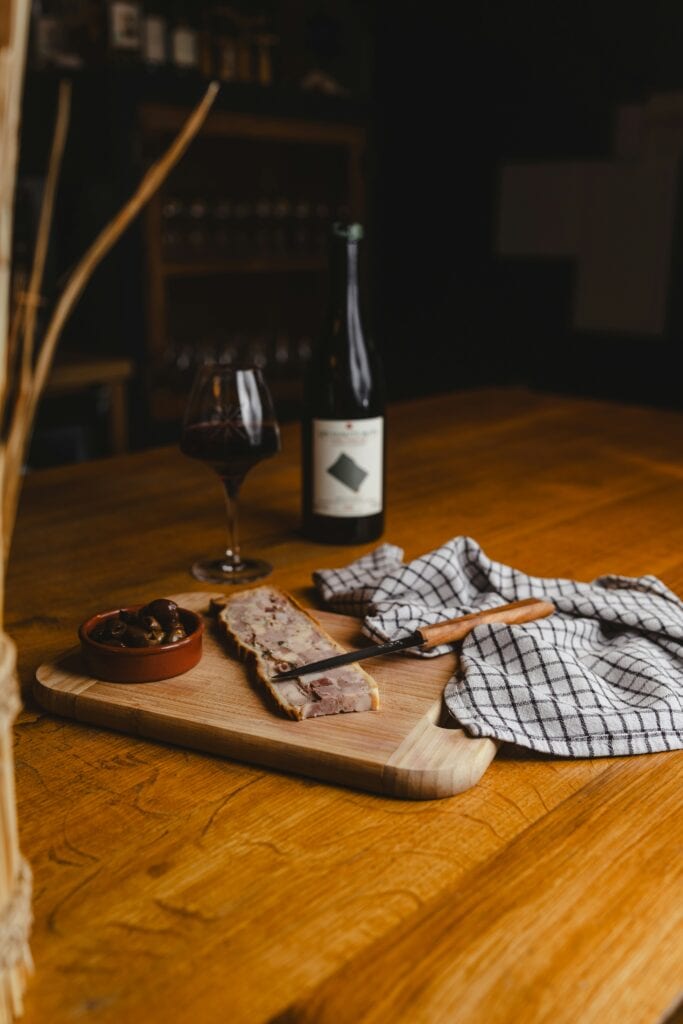 French pâté terrine on a wooden board with olives and red wine
