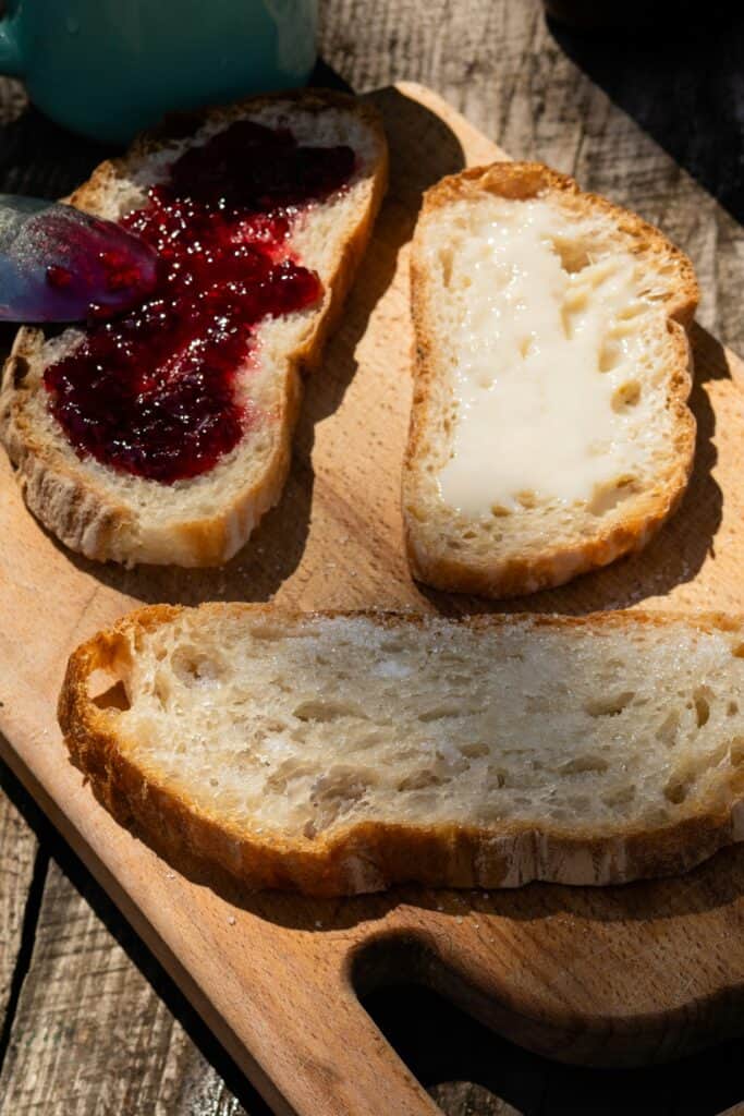 French tartine breakfast with bread, butter and jam on a wooden board