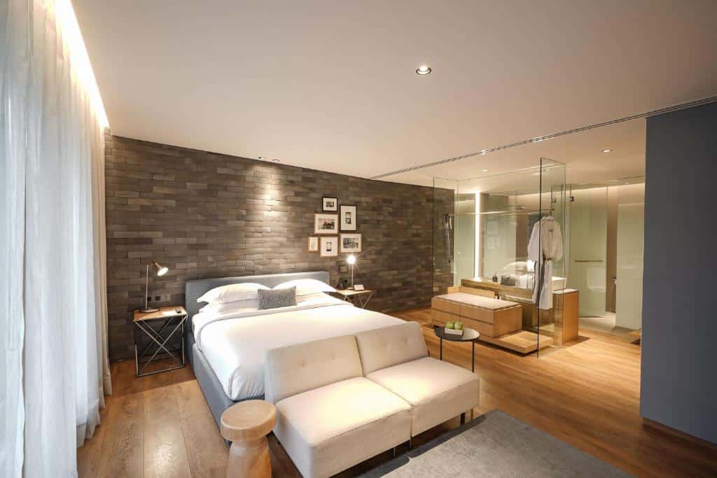Modern suite at Ad Lib Bangkok with warm wood interiors, brick walls and open-plan bathroom design