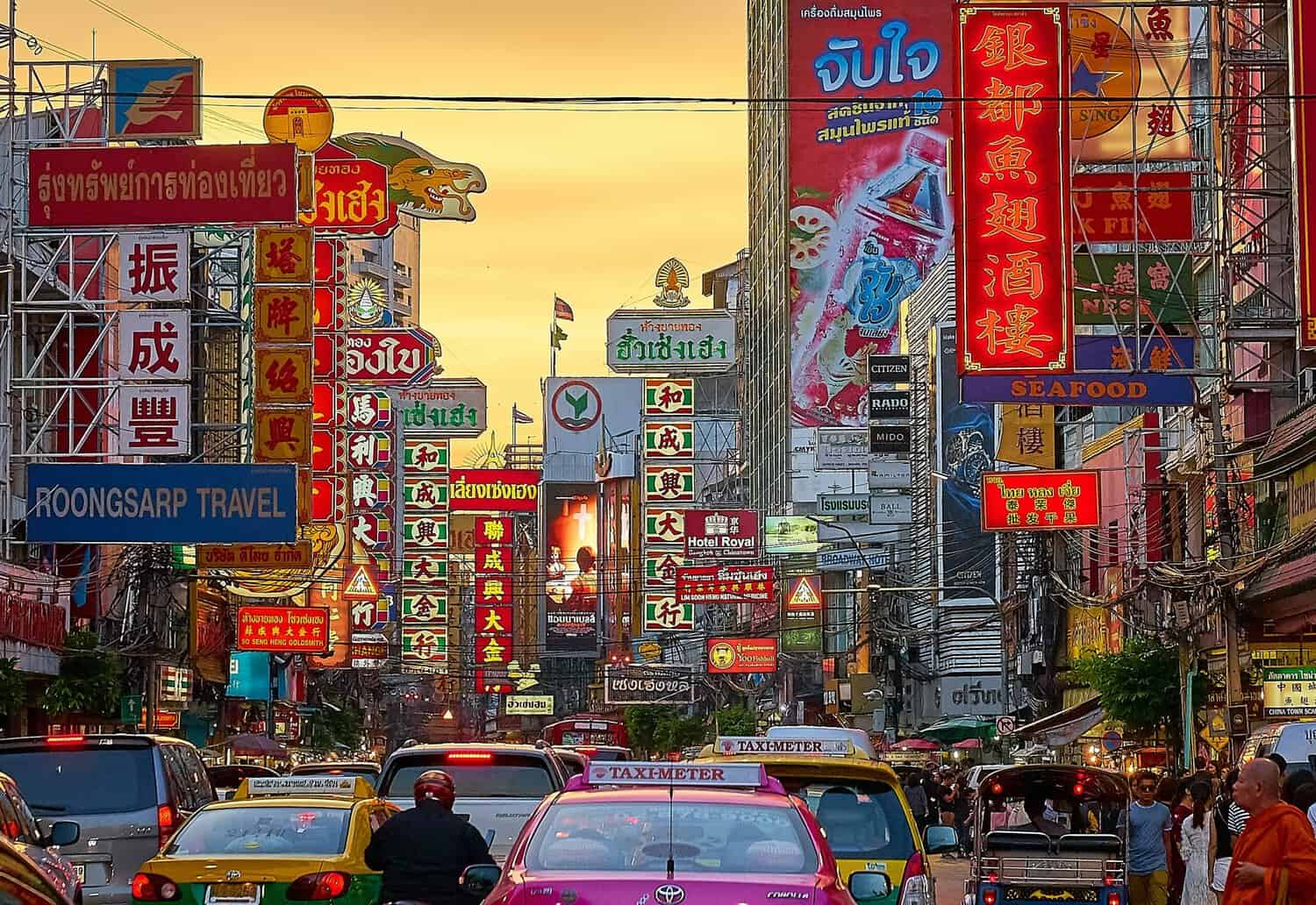 Busy Bangkok Chinatown street with neon signs, traffic and crowded Yaowarat Road at sunset
