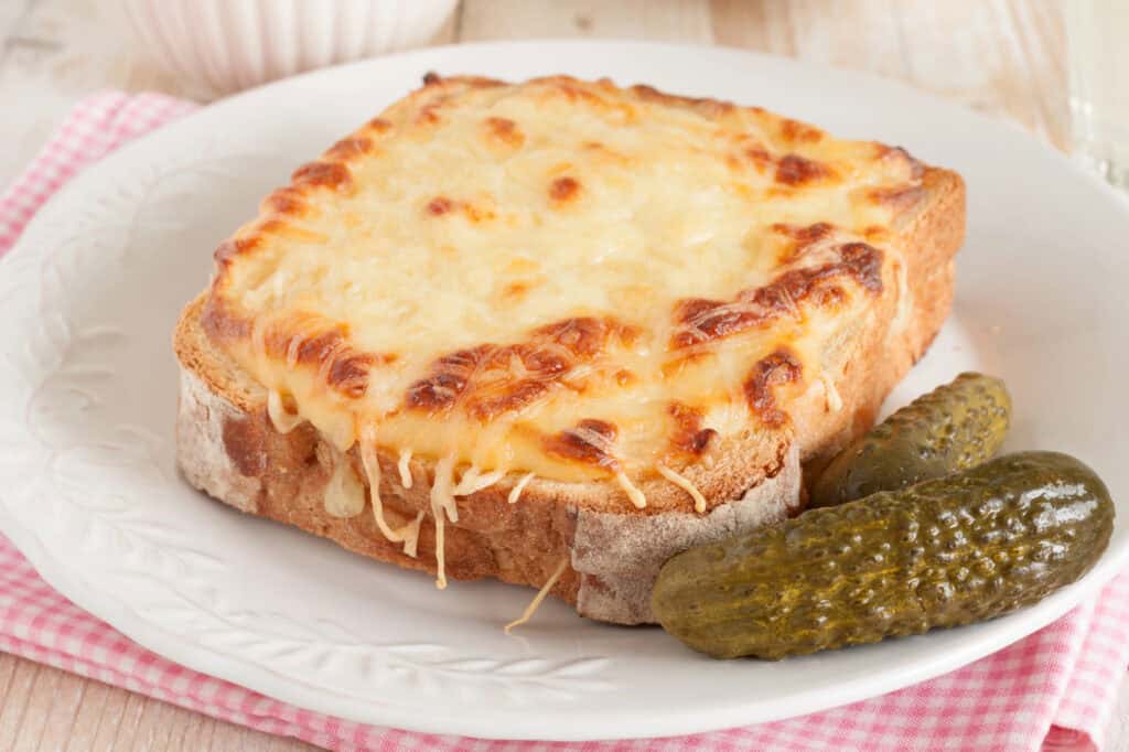 Croque Monsieur on a white plate with a gherkin