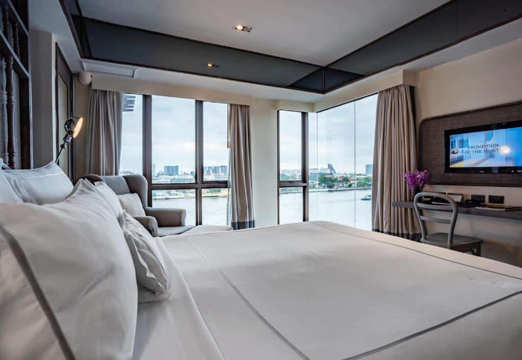 “Riverside bedroom at Riva Surya Bangkok with balcony and water view”