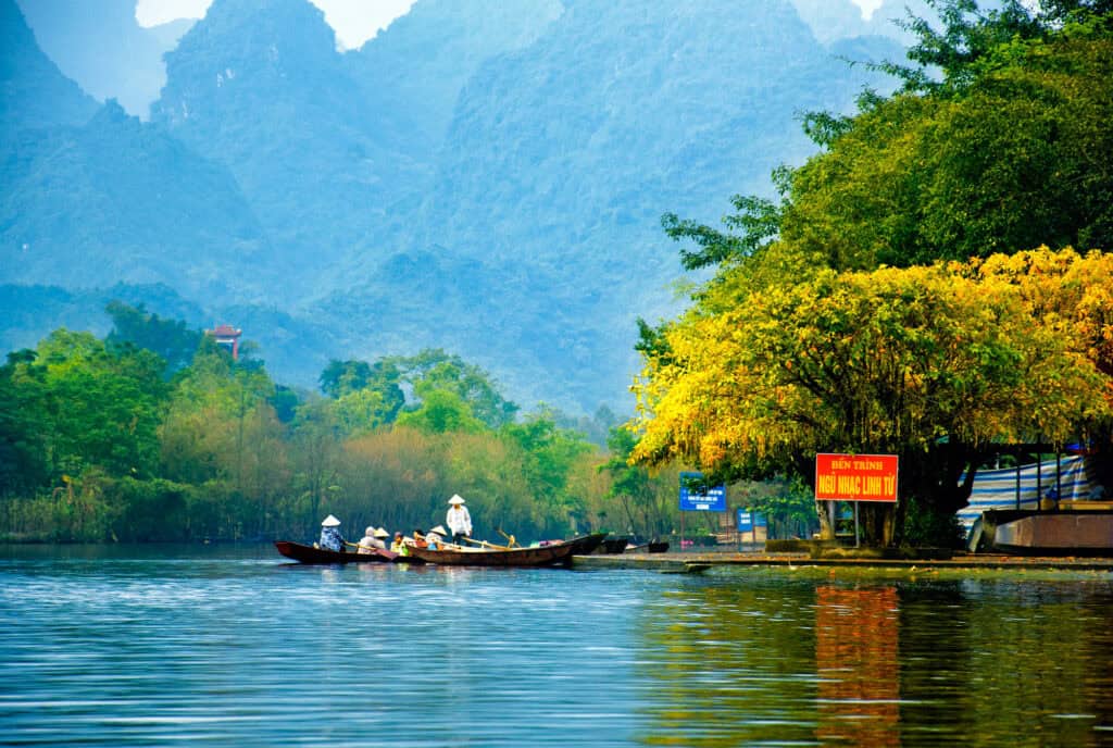Boats floating on the Yen Stream surrounded by autumn foliage on the way to the Huong Pagoda, Hanoi, Vietnam