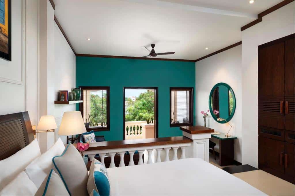 Spacious riverside hotel room with balcony and colonial-style decor in Hoi An, Vietnam.