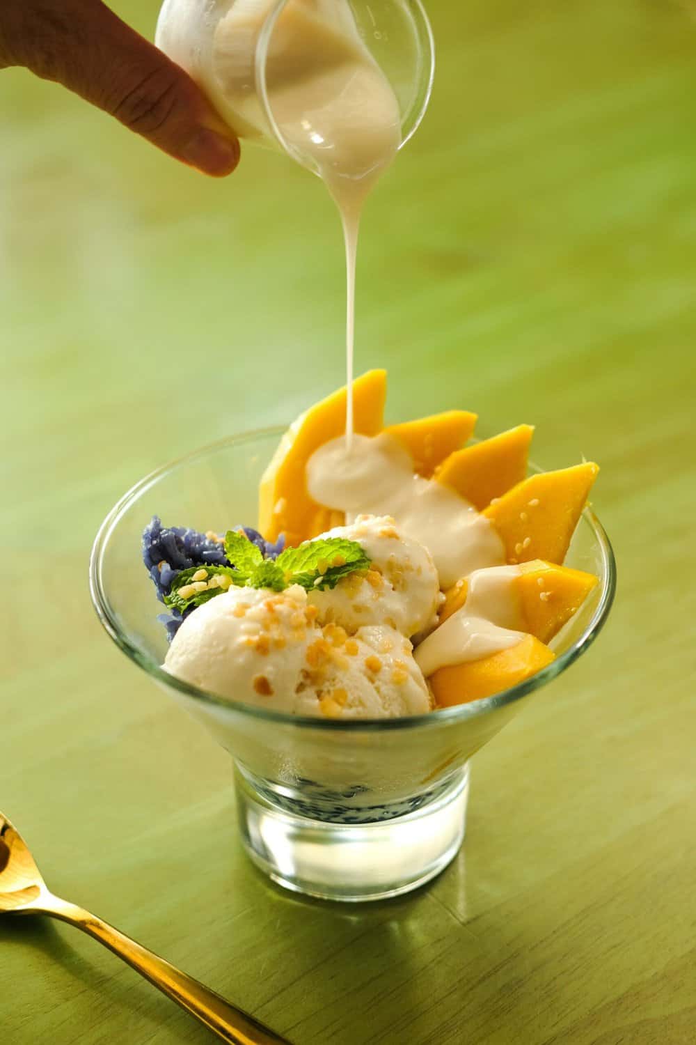 Plate of ripe mango slices served with sticky rice and coconut cream, a popular Vietnamese dessert.