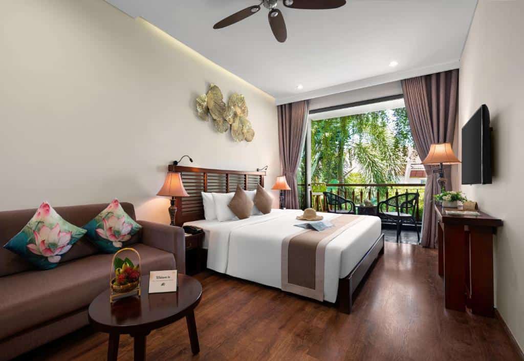 Spacious bedroom with modern eco-friendly design and balcony at Silk Sense Hoi An River Resort.