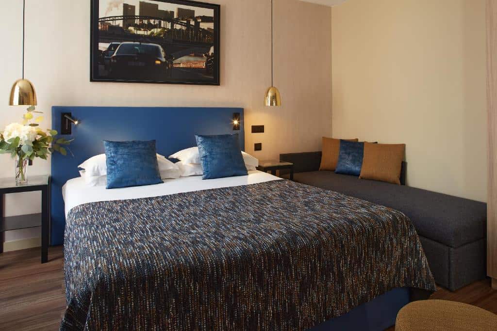 Modern hotel bedroom at Hôtel Atmosphères in the Latin Quarter, Paris, with contemporary furnishings, blue accents, and a compact seating area