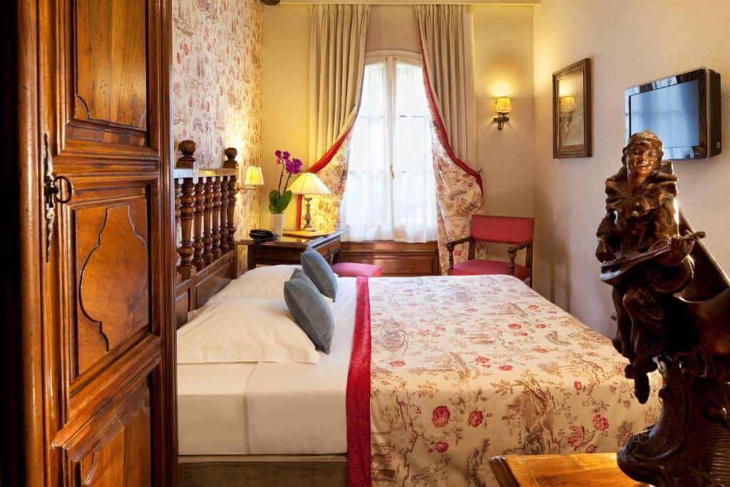 Traditional bedroom at Hôtel Left Bank Saint-Germain in Paris, with wooden furniture, patterned fabrics, and a small double bed in a classic Left Bank setting
