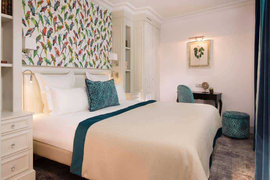 Bright boutique hotel bedroom at Hôtel Monge in the Latin Quarter, Paris, with patterned wallpaper, neutral furnishings, and a comfortable double bed