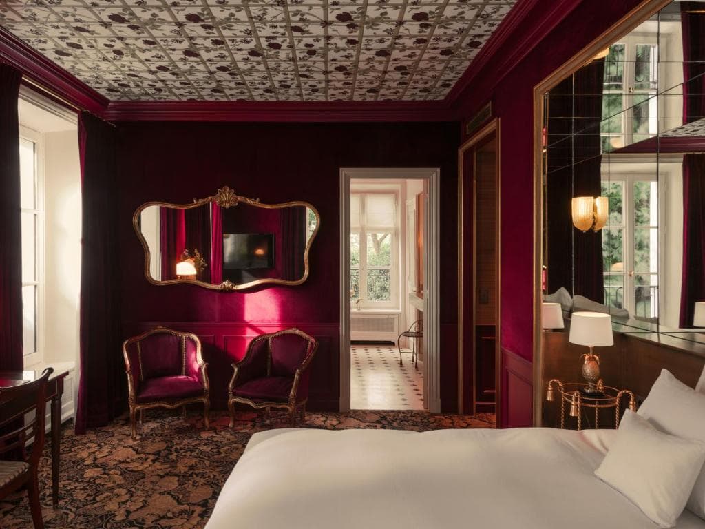 Luxurious suite at Hôtel Particulier Montmartre in Paris, featuring deep red walls, vintage furnishings, and ornate detailing in a private townhouse setting