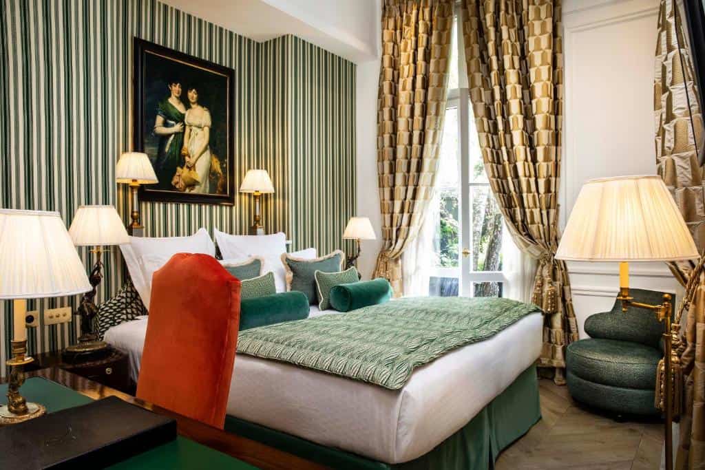 Classic bedroom at Relais Christine in Saint-Germain-des-Prés, Paris, with patterned fabrics, striped walls, and tall windows overlooking a quiet courtyard