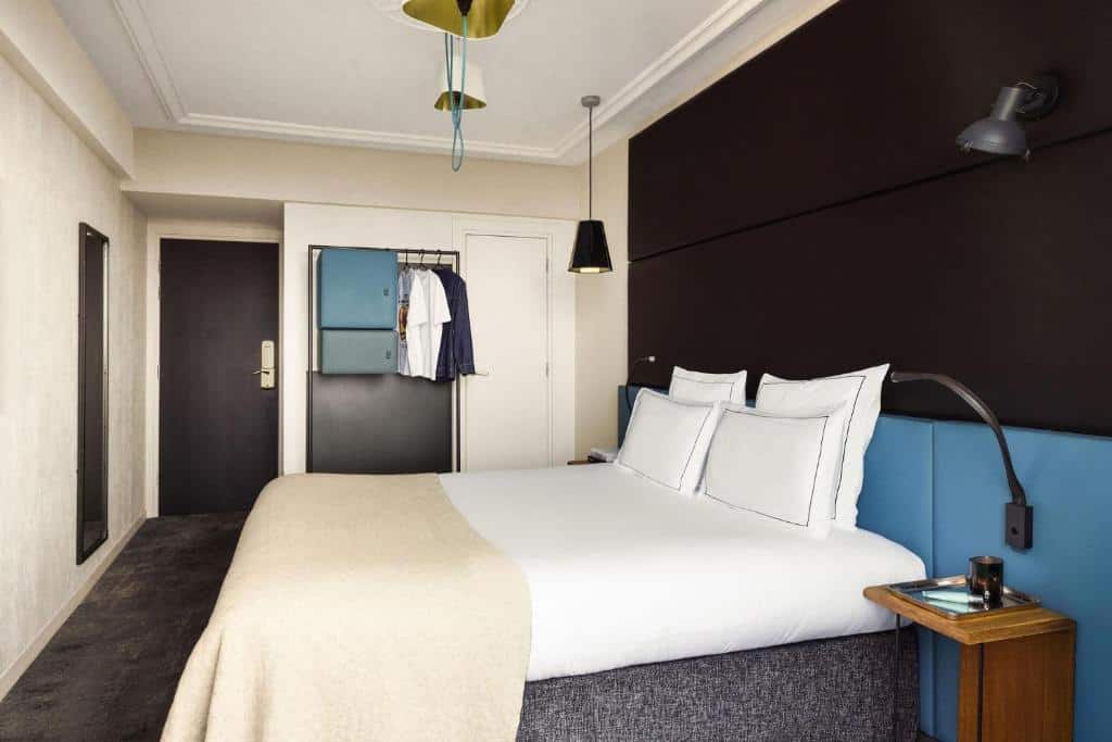 Contemporary hotel bedroom at Terrass’ Hotel in Montmartre, Paris, with clean-lined furnishings, neutral tones, and a compact seating area