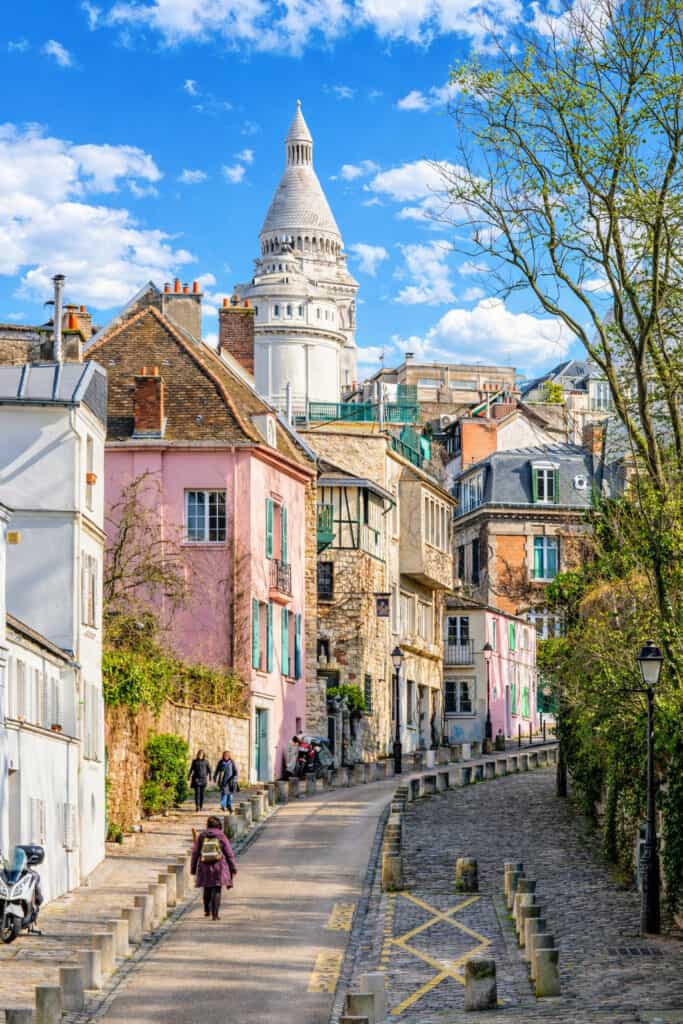 Montmartre street with colourful houses and Sacré-Cœur Basilica above the rooftops in Paris.