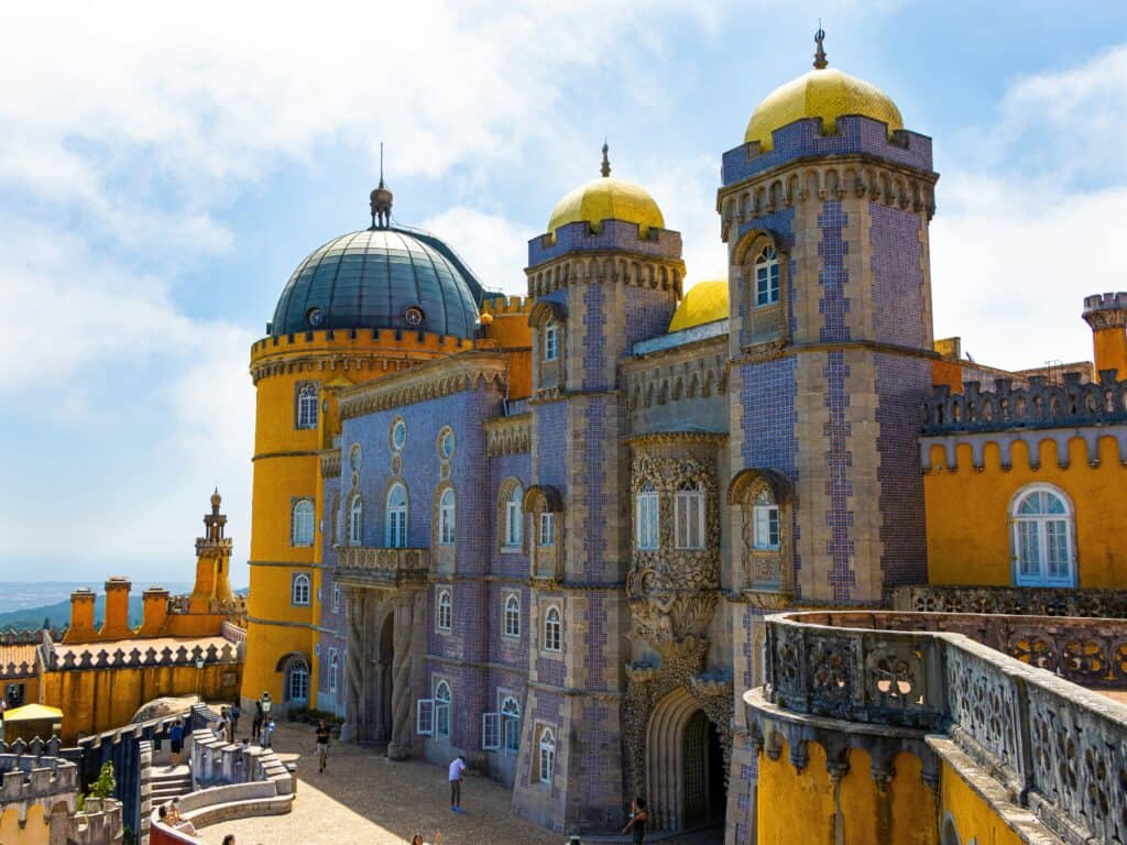 Pena Palace in Sintra with yellow and blue towers, domes, and ornate architecture overlooking the surrounding hills