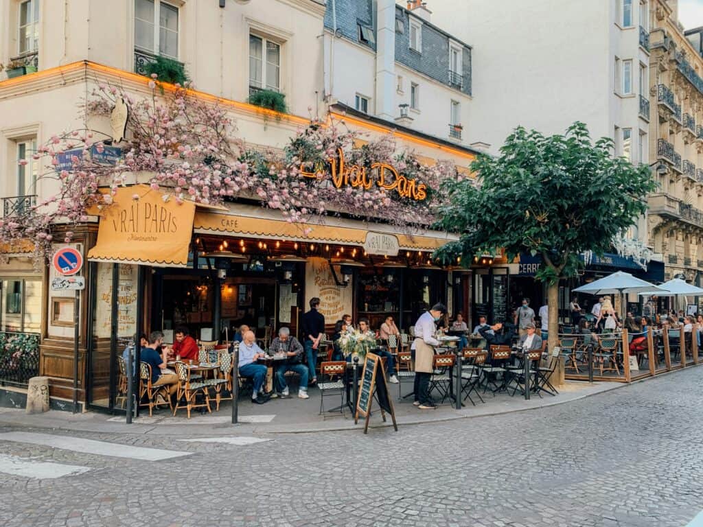 Traditional Paris café terrace with outdoor dining and people seated outside a Montmartre restaurant